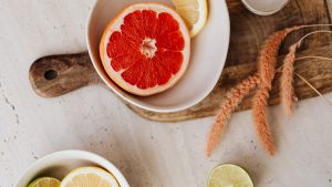 Overhead view of a grapefruit, lemon, and lime arrangement in bowls on a rustic wooden chopping board.